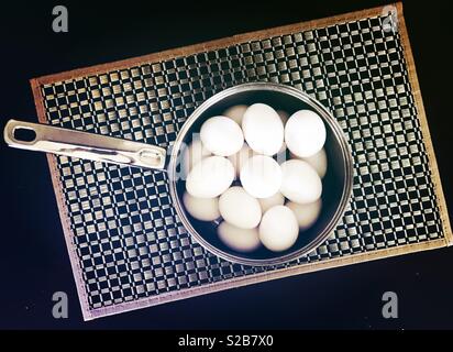 Belle et lumineuse des œufs blancs dans un pot d'argent affiche sur un napperon damier dans la cuisine Banque D'Images