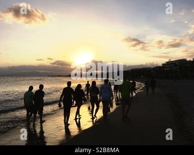 Un groupe d'adolescents en marchant sur une plage au coucher du soleil sur la Costa Dorada à Salou, Catalogne, Espagne Banque D'Images