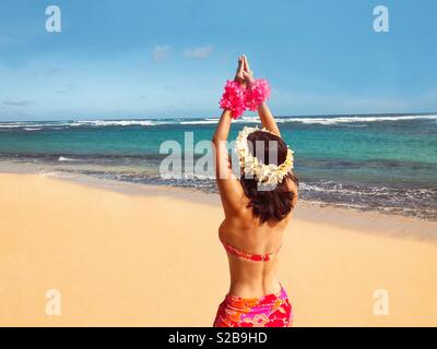 Princesse d'Hawaii hula dancer sur la plage déserte de l'île du Pacifique ornée de motifs floraux et d'appariement de bikini paréo, fleurs, fleur, leis dans les mains, les cheveux Banque D'Images