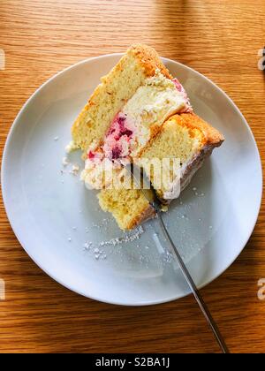 Morceau de gâteau avec de la crème fraîche et aux fraises garniture sur une assiette blanche Banque D'Images