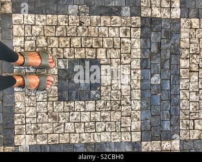 Femme se dresse sur une rue pavée à motifs. Banque D'Images