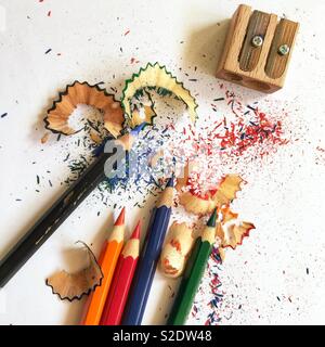 Plusieurs crayons de couleur étant avivée par taille-crayon en bois avec de jolis copeaux colorés cannelé sur la surface blanche Banque D'Images