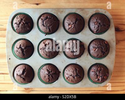 Mise à plat de la puce au chocolat maison muffins courgettes dans un bac métallique sur table en bois Banque D'Images
