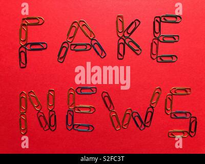 Fake News écrit en trombones sur fond rouge Banque D'Images