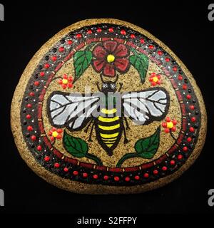Un rocher peint avec une abeille et roses avec une bordure rouge et noir... abeille populations ont lutté au cours de la dernière décennie et ont finalement commencé à rebondir. Banque D'Images