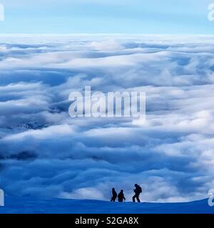 Trois skieurs surplombant une mer de nuages. Pris sur le mont Titlis, Engelberg, Suisse. Banque D'Images