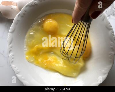 Battre les oeufs dans un bol blanc Banque D'Images