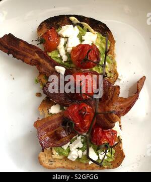 Plaque de base de l'avocat, le fromage feta, tomates et bacon sur toast Banque D'Images