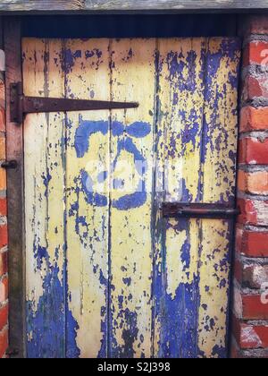 Vieille peinture écaillée sur une porte des toilettes à l'extérieur. Banque D'Images