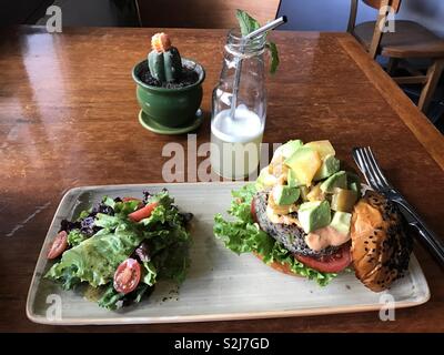 Hamburger Vegan à l'avocat et la mangue servi avec une salade verte et de jus de lime frais dans une bouteille en verre avec une paille d'acier. Photo taken in Cusco, Peru Banque D'Images