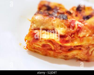 Vue rapprochée d'une partie de la lasagne italienne servi dans une assiette blanche Banque D'Images