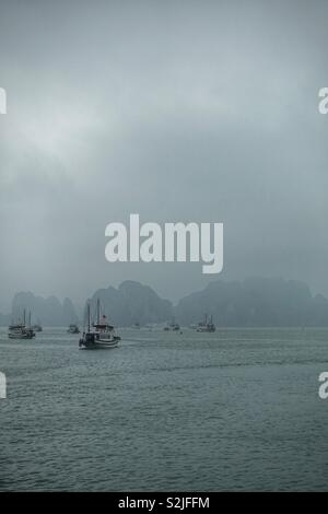 La baie de Ha Long au Vietnam. Jour de pluie, brume, brouillard. Avec fisherboats amarrés. Banque D'Images