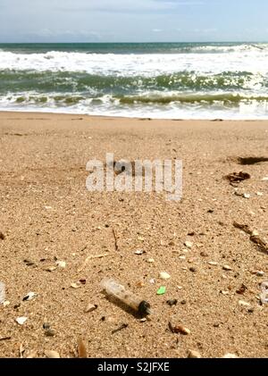 Pollution : seringue utilisée et abandonnée sur une plage de la mer tropicale. Banque D'Images