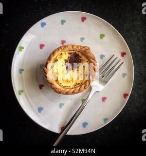 Vue du haut vers le bas d'un flan sur une assiette à motifs blancs avec une fourchette Banque D'Images