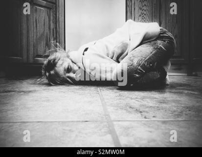 Moody image de jeune fille recroquevillée sur le sol de la cuisine se sentir triste et en colère Banque D'Images