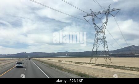 Des pylônes électriques à haute tension câbles de l'électricité traverse l'Interstate 15 près de générateurs d'énergie solaire massive. Désert de Mojave, en Californie. Banque D'Images