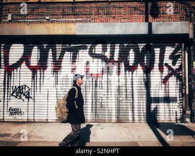 Un homme passe devant une porte sur laquelle les mots "Don't Shoot" sont peintes dans le graffiti Banque D'Images