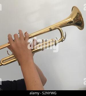 Enthousiaste garçon de 12 ans pratiquant sur sa nouvelle trompette brillante avant sa leçon de trompette et la pratique d'orchestre. Banque D'Images