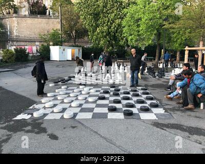 Les hommes aînés jouant ou traites de pions sur un grand échiquier jeu sur le terrain du Parc des Bastions - Genève Suisse Banque D'Images