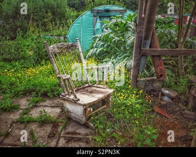 Le jardin luxuriant et un fauteuil à bascule en bois Banque D'Images