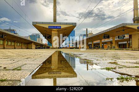 Train sur la plate-forme à la gare de Bruxelles reflété dans une flaque d'eau après la pluie Banque D'Images