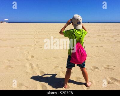 Vue arrière d'un boy standing on beach Banque D'Images