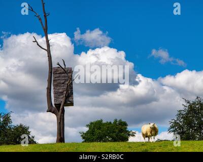 Les moutons à côté de la sculpture d'un arbre au Yorkshire Sculpture Park, près de Wakefield West Yorkshire Angleterre UK Banque D'Images