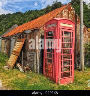 Boîte de téléphone rouge contre des bâtiments délabrés. Banque D'Images