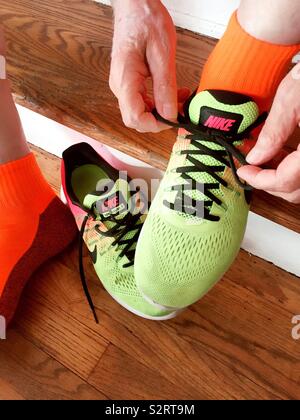 Caucasian man lier les lacets de ses chaussures de course au néon de couleur vibrante, United States Banque D'Images