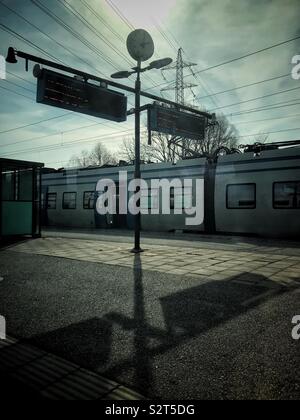 Un train de banlieue local s'arrête à une station sur une journée ensoleillée avec des ombres à Stockholm, Suède Banque D'Images