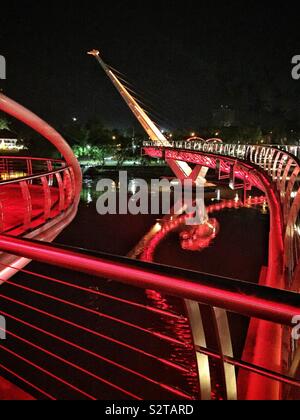 Le Darul Hana Bridge, qui permet aux piétons de traverser la rivière Sarawak Kuching Waterfront de la cité pour l'Édifice de l'Assemblée législative de l'État de Sarawak, Malaisie, illuminée la nuit, Banque D'Images