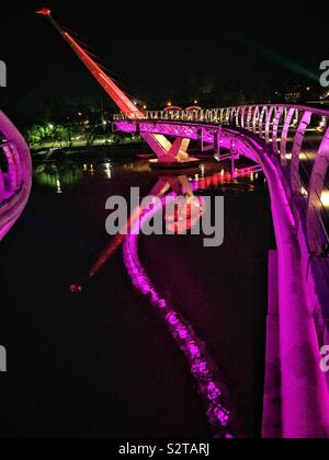 Le Darul Hana Bridge, qui permet aux piétons de traverser la rivière Sarawak Kuching Waterfront de la cité pour l'Édifice de l'Assemblée législative de l'État de Sarawak, Malaisie, illuminée la nuit, Banque D'Images