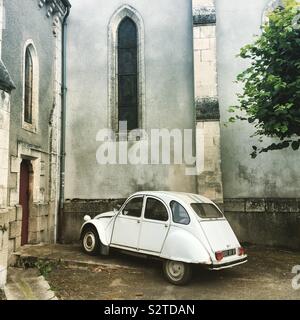 Un vieux livre blanc "deux chevaux" voiture garée en face d'une église dans un village français Banque D'Images