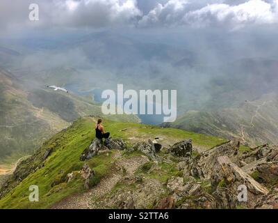 Jeune femme admirant la vue sur Llyn Llydaw de Snowdon avec une mouette voler passé. Banque D'Images