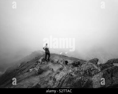 Homme d'âge moyen contemplant la vue à travers les nuages bas du mont Snowdon, Eryri. Banque D'Images