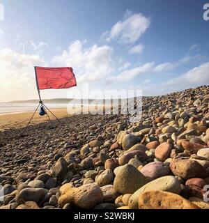 Drapeau rouge sur une plage. Banque D'Images