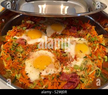 Les œufs avec bacon de dinde et de légumes râpés dans une poêle Banque D'Images