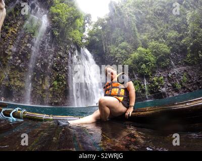 Une femme assise sur un bateau en bambou en face de Tinago Falls à Illigan City aux Philippines. Banque D'Images