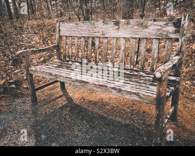 Banc en bois patiné à l'extérieur dans un jardin boisé. Banque D'Images