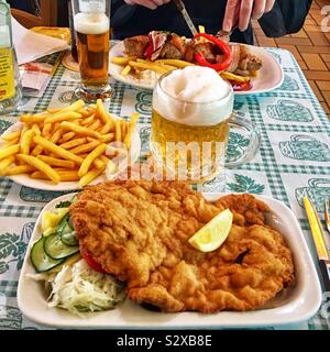 Wiener Schnitzel avec Choucroute, salade de concombre, salade de pommes de terre, frites et de la bière Oktoberfest Radler pendant à Vienne, Autriche Banque D'Images