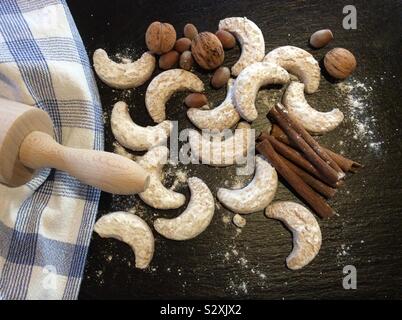 Croissant à la vanille vanille kipferl (cookies) à Noël. Un rouleau à pâtisserie, les écrous et les bâtonnets de vanille sur fond noir Banque D'Images