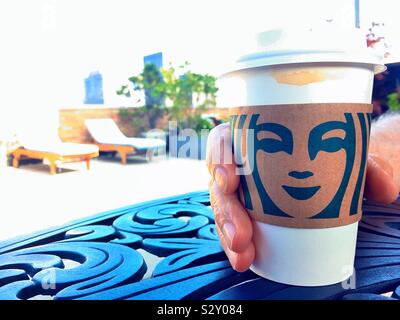 L'homme jouissant d'une tasse de café Starbucks avec un manchon en carton sur sa toiture-terrasse patio à Midtown Manhattan, New York, USA Banque D'Images