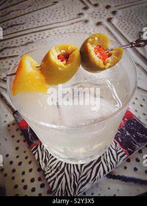 Martini sur les rochers dans un verre de cristal à moitié mangé les olives et une tranche de citron. Banque D'Images