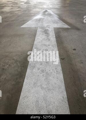 Peint en blanc Flèche indiquant une direction d'un sol en béton. Banque D'Images