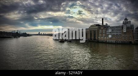 Vue panoramique sur la Tamise, avec Butler's Wharf à droite et Canary Wharf et d'autres gratte-ciel à droite sous un ciel couvert le matin. Banque D'Images