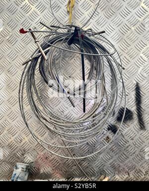 Des câbles d'acier et les broches en face d'un mur d'acier checker plate Banque D'Images