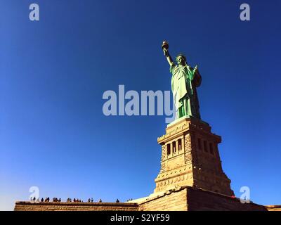 Les touristes affluent au socle de la Statue de la liberté sur Liberty Island à New York Harbor sur une journée sans nuages bleu clair, NYC, USA Banque D'Images