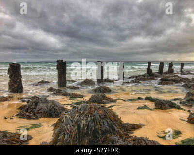 Plus de lavage vagues vieux bois épis dans de mauvaises conditions météorologiques à St Ives, Cornwall, en octobre. Banque D'Images