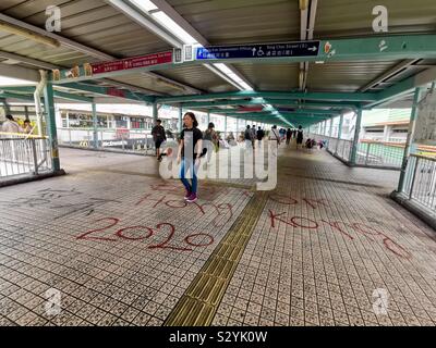 Les piétons circulant sur des slogans graffiti peint par manifestants exiger leurs droits à Hong Kong. Banque D'Images