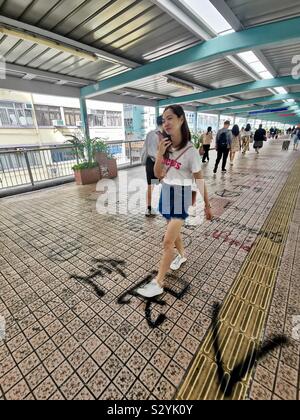 Les piétons circulant sur des slogans graffiti peint par manifestants exiger leurs droits à Hong Kong. Banque D'Images